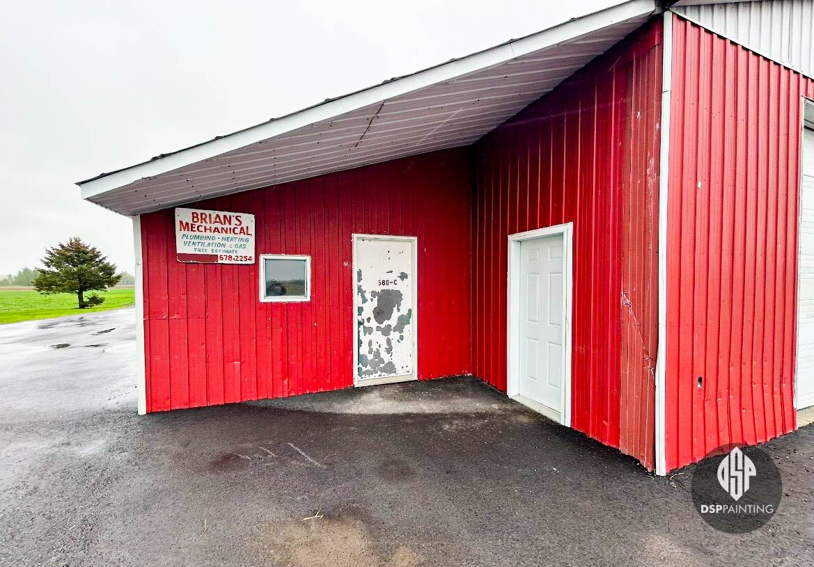 The same garage before painting, with faded red siding and paint flaking off the service door