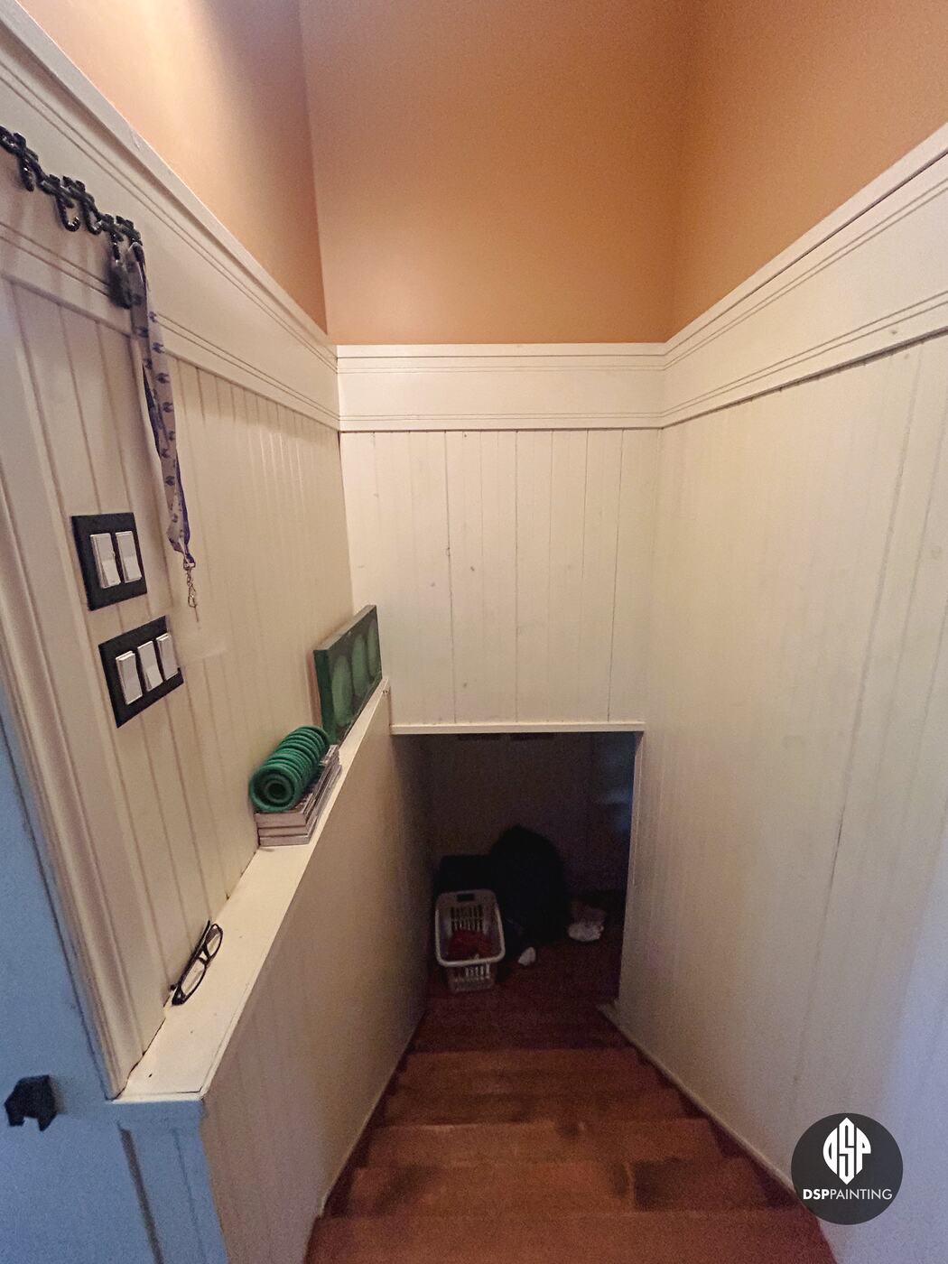 The stairwell before painting, peach walls and ceiling above cream tongue-and-groove panelling down to the basement
