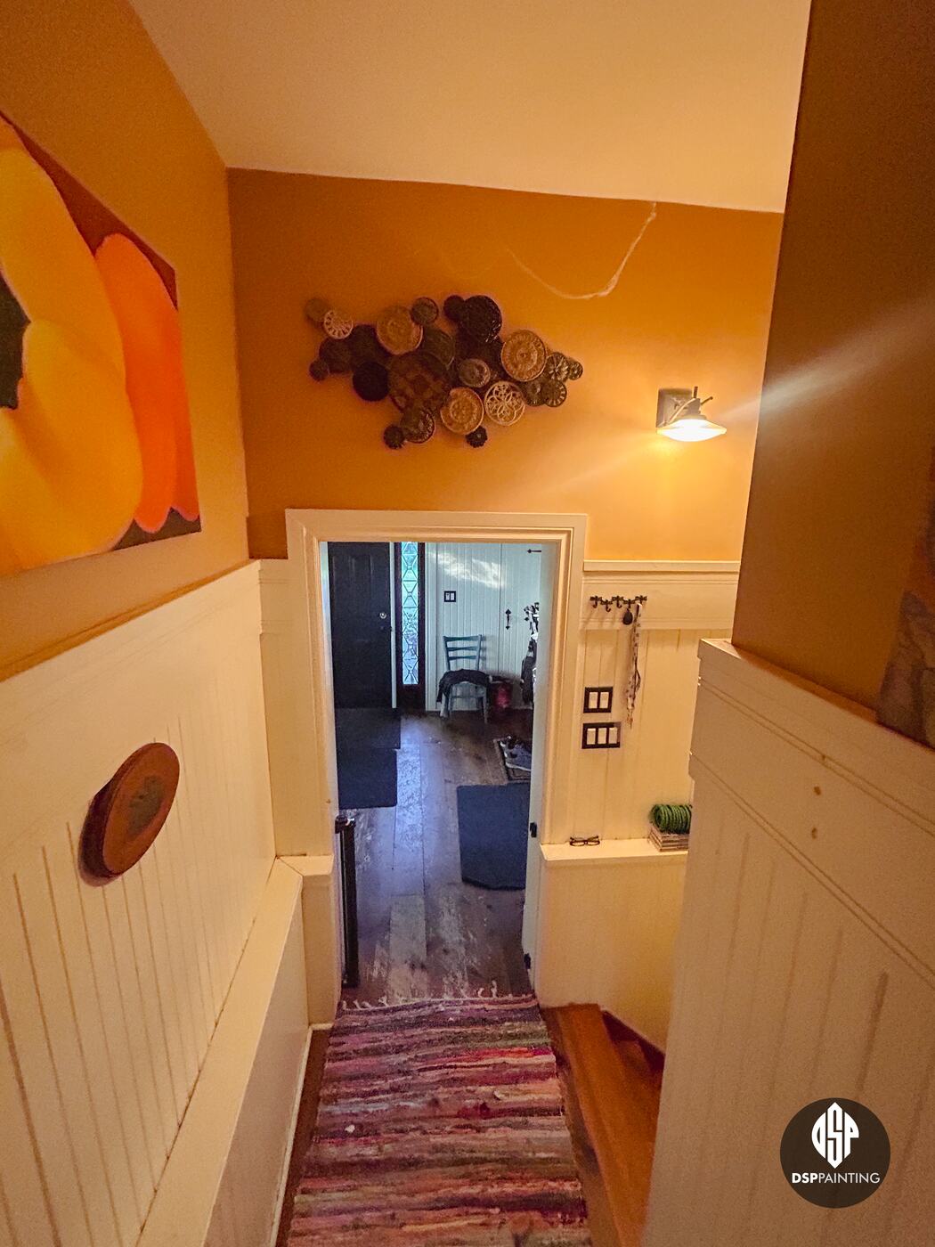 Looking down the stairs before painting, burnt-orange walls above cream wainscoting