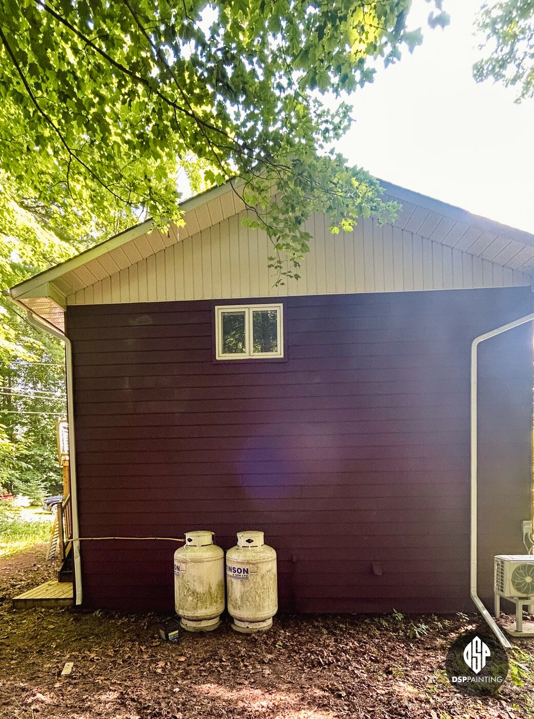The same gable end from further back, red-brown siding under the cream gable and a white downspout