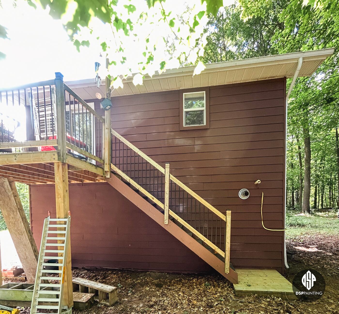 The back wall and the wooden stairs up to the deck, the siding in red-brown