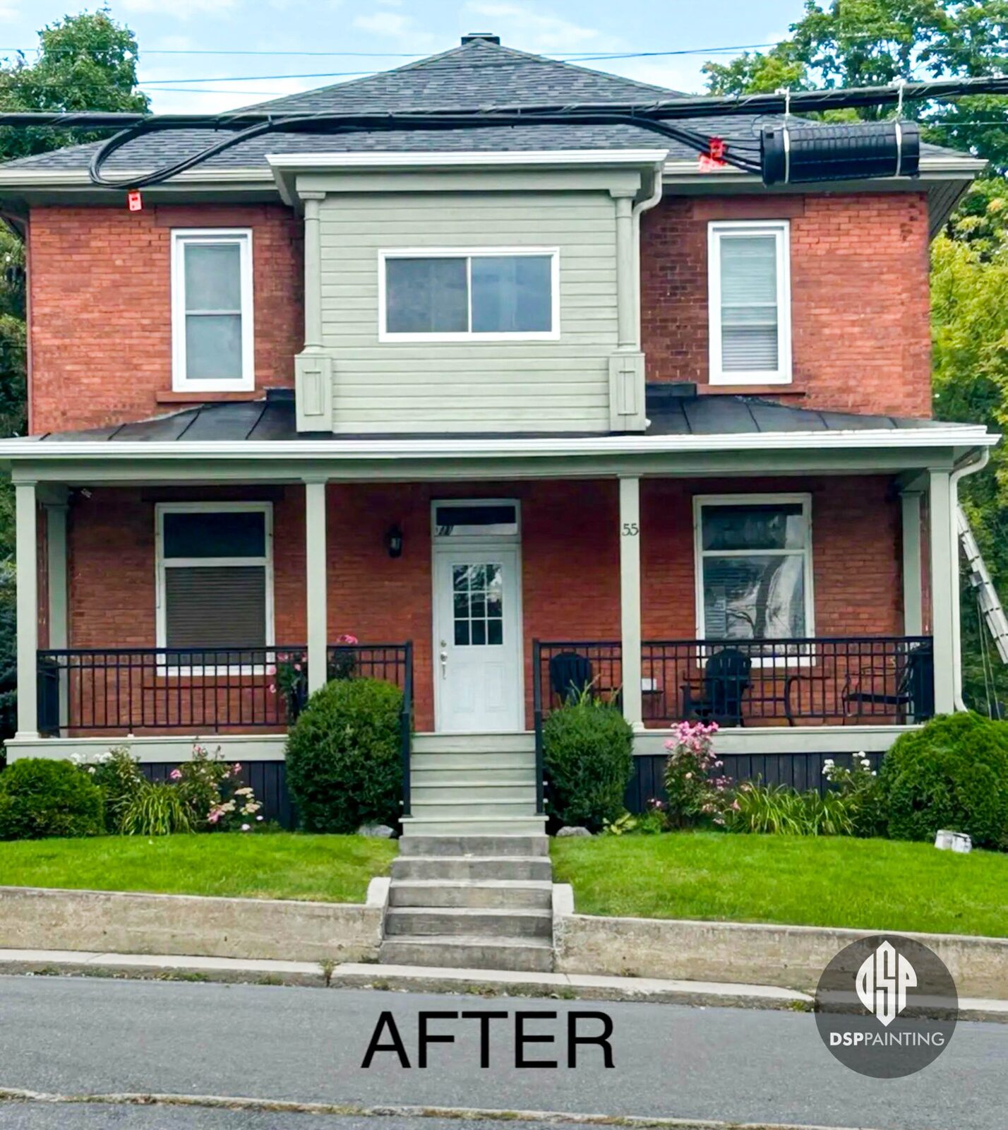 A red-brick two-storey house with its porch columns, railings, window trim and upper gable siding painted sage green