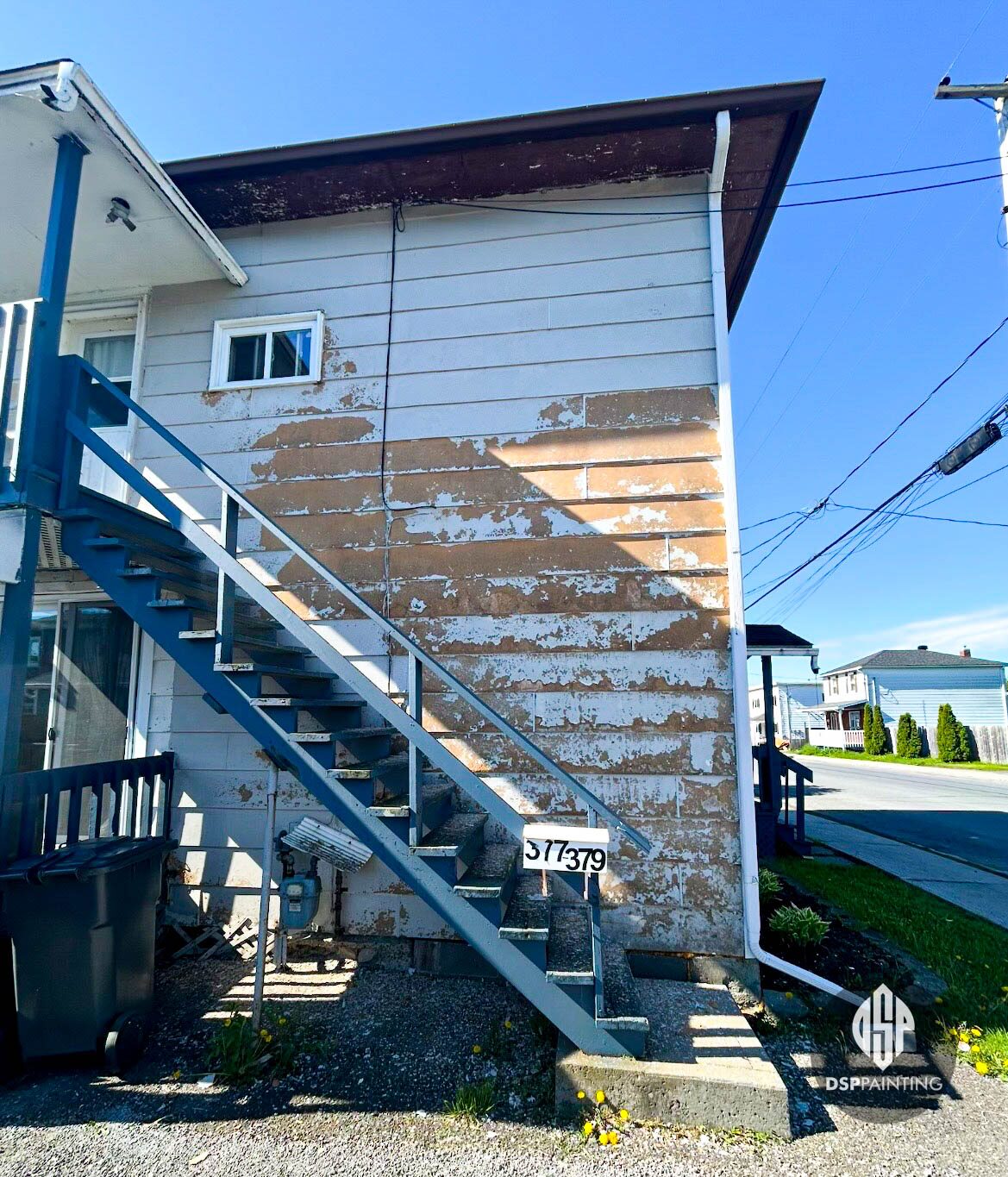 Side wall before painting, with paint flaking away from the clapboard beside the exterior stairs
