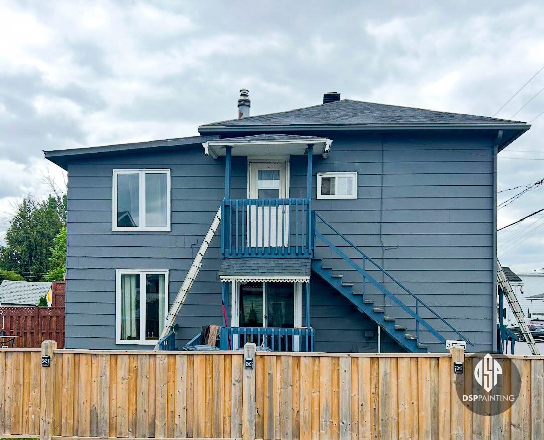 Back of the same house, slate grey siding carried around behind the exterior staircase and balcony