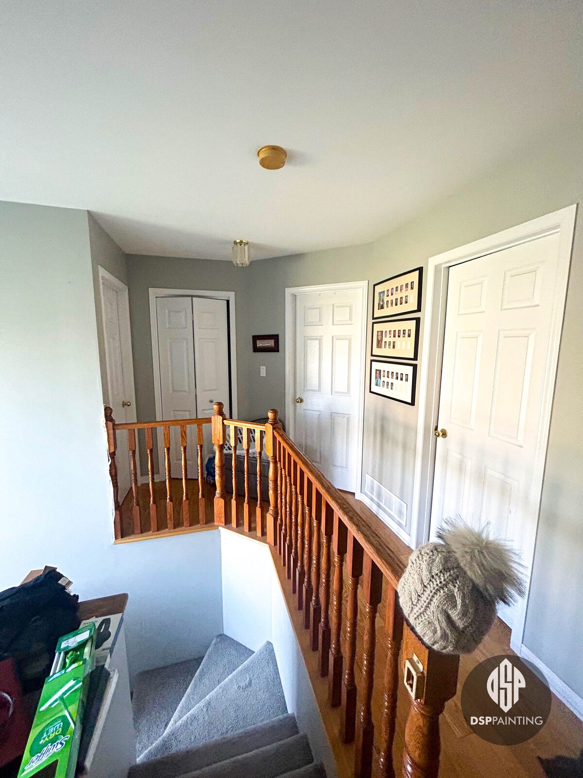 Upstairs landing before the work, with white panel doors, a varnished oak banister and grey walls