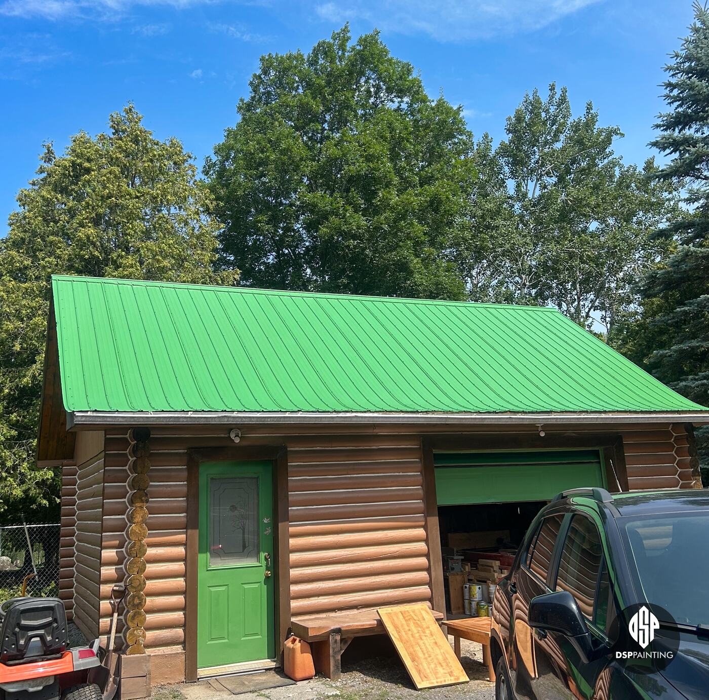 The log garage up close, its roof painted bright green above the green service door