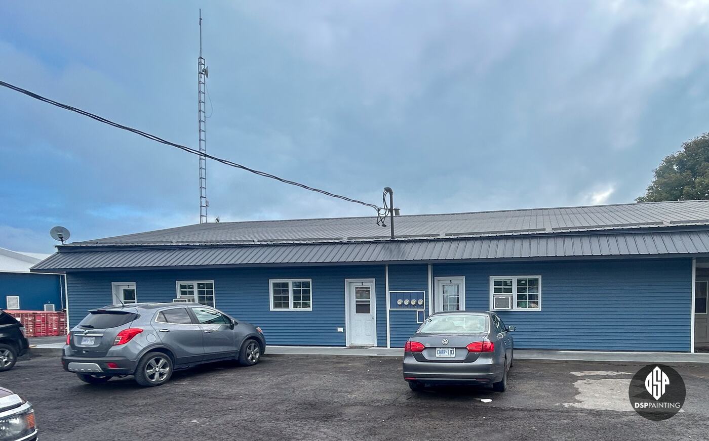 The long single-storey wing after the work, its metal roof painted charcoal above blue siding